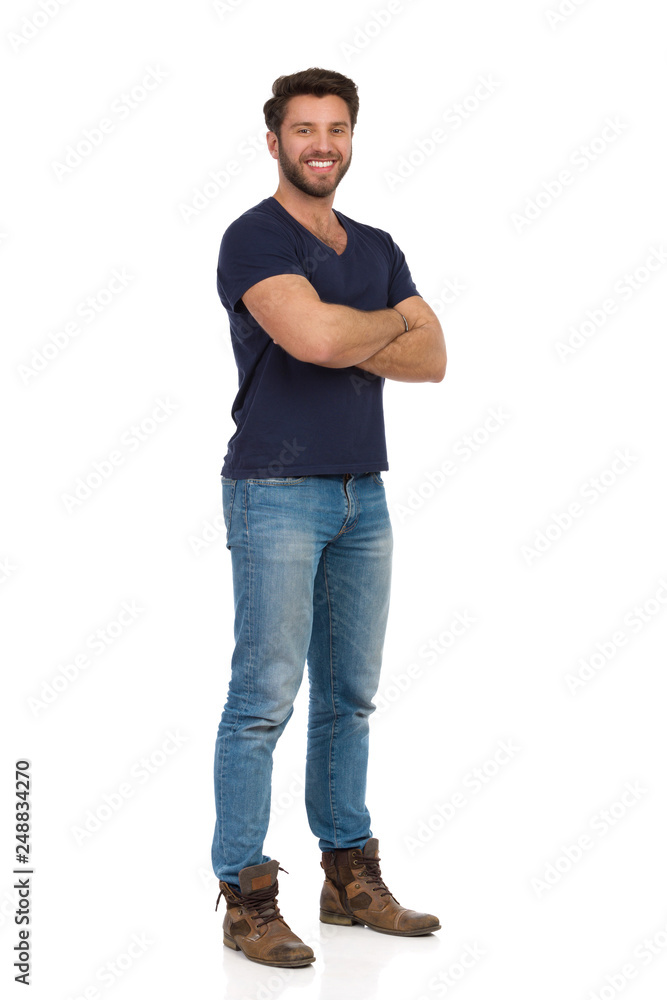 Young Man In Jeans And Blue T-shirt Is Standing With Arms Crossed Young Man In Jeans And Blue T-shirt Is Standing With Arms Crossed