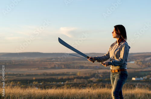 Girl on a high mountain trains with a machete in the evening at sunset