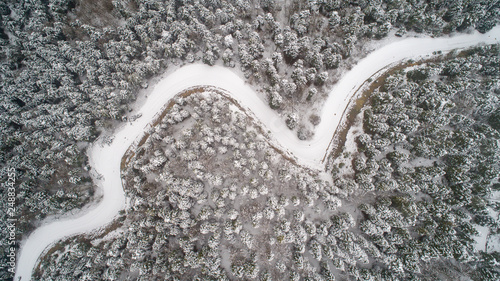Aerial view of winding road and cars from high mountain pass with snow-covered trees in winter time © yusufozluk