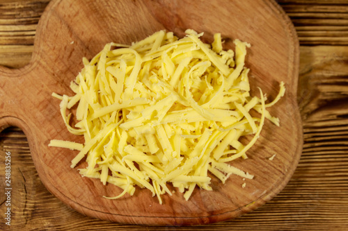 Grated cheese on cutting board on wooden table