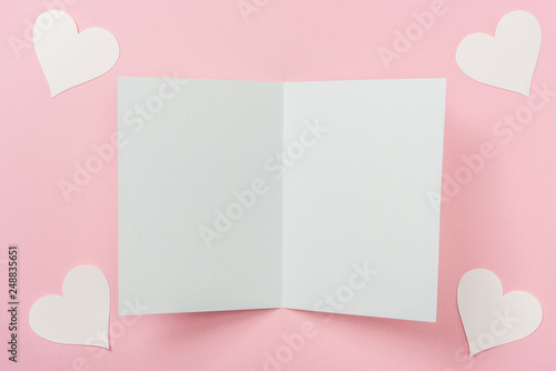 blank greeting card and white paper hearts on pink background © LIGHTFIELD STUDIOS