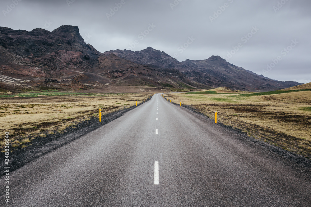Straight forward asphalt road among rocky volcanic landscape of Reykjanes Peninsula in Iceland on a cloudy summer day