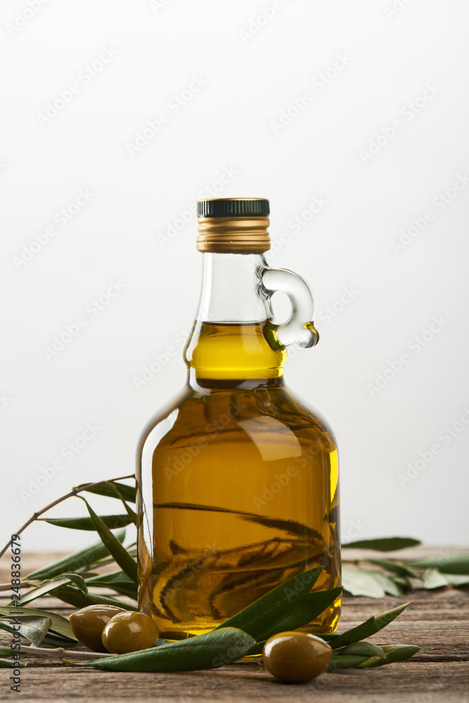 bottle of oil with olive tree leaves and olives isolated on grey