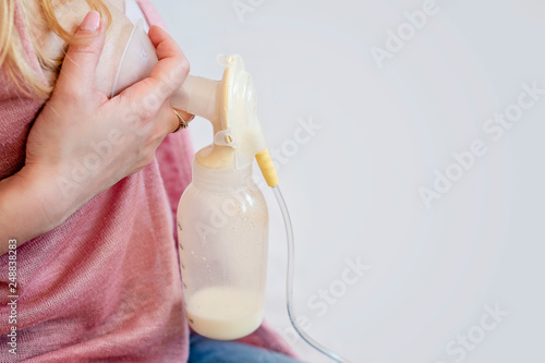 Young mother is using single electric breast milk pump and pumping breast milk for her baby. Breast milk for supplementary feeding, infant nutrition. - image