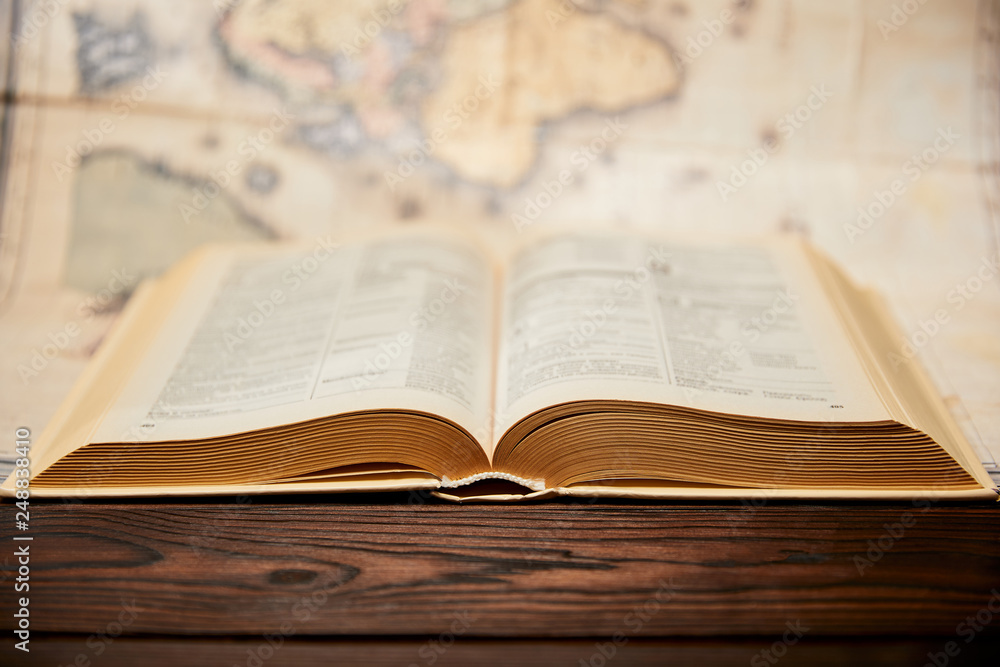 Selective focus of book and map on wooden table Selective focus of book and map on wooden table