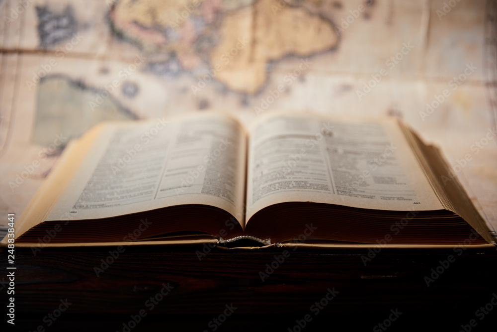 Selective focus of book and map on wooden table Selective focus of book and map on wooden table