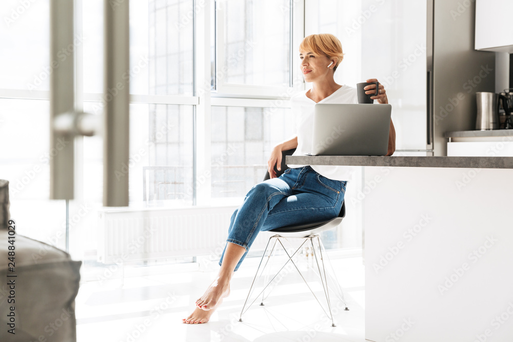 Smiling woman casualy dressed using laptop computer Smiling woman casualy dressed using laptop computer