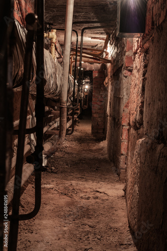 A long tunnel of an old abandoned basement. Basement with pipes and lamps on the sides
