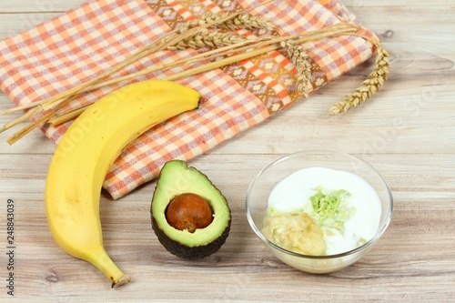 Ingredients for easy homemade facial mask. Banana, avocado, honey, olive oil, oatmeal and soured cream good for face mask, wood board