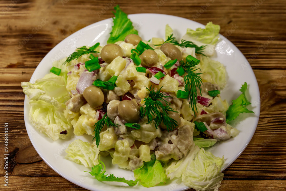 Potato salad with marinated mushrooms, eggs, red onion and mayonnaise on wooden table Potato salad with marinated mushrooms, eggs, red onion and mayonnaise on wooden table
