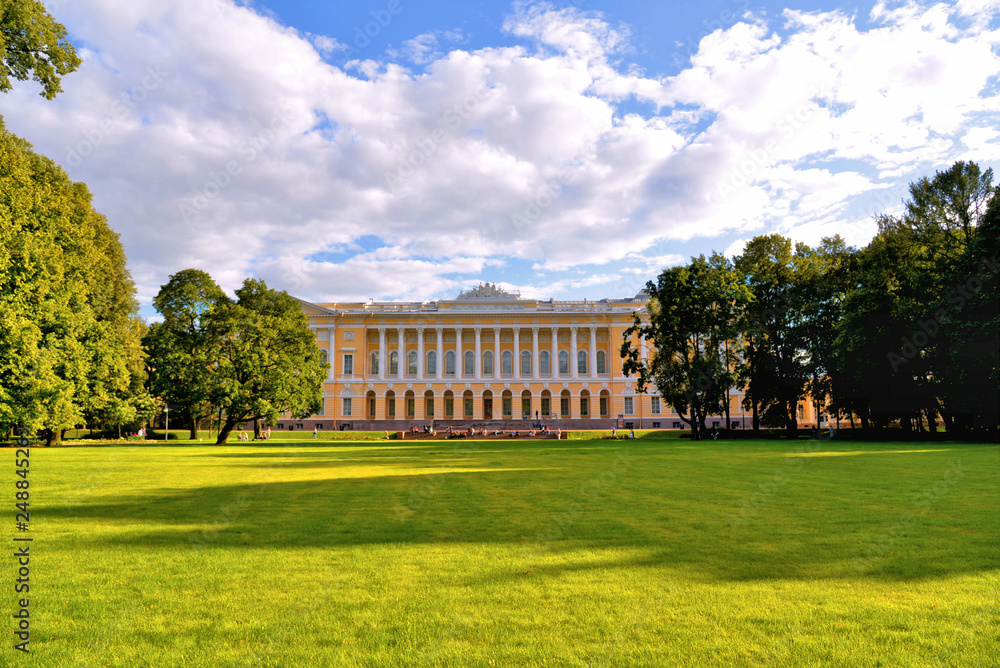 Obraz premium St Petersburg, Russia Northern facade of Mikhailovsky palace, building of the State Russian museum with green park with people and scenic blue cloudy sky.