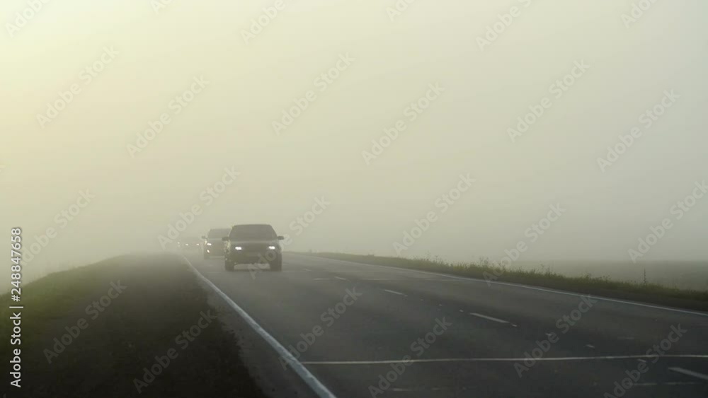 car riding along highway among green fields in foggy morning car riding along highway among green fields in foggy morning