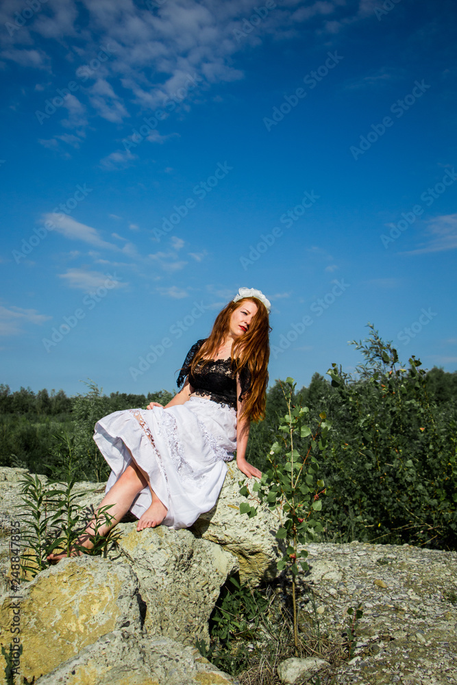 Young redhead girl sitting on the rock Young redhead girl sitting on the rock