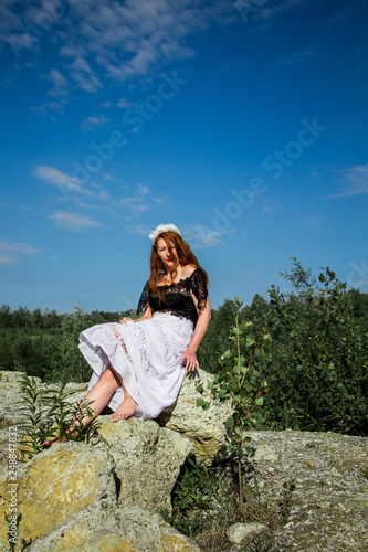 Young redhead girl sitting on the rock 