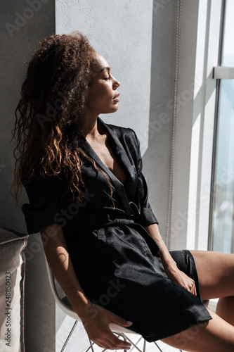 Portrait of stylish african american woman wearing housecoat, sitting near window indoor Free Download Portrait of stylish african american woman wearing housecoat, sitting near window indoor - GFXLoad