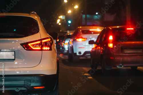 Traffic jam in evening rush hour, blurred night city lights and car headlights, abstract concept of urban transportation and exhaust pollution