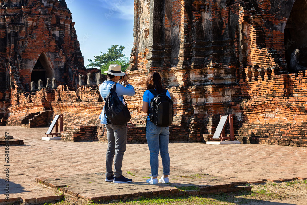 Eastern Asia summer holidays. Caucasian man and Asian woman tourist from back looking at Wat Chaiwatthanaram temple. Tourist travel in the morning at temple in old city of Ayutthaya in Thailand.
