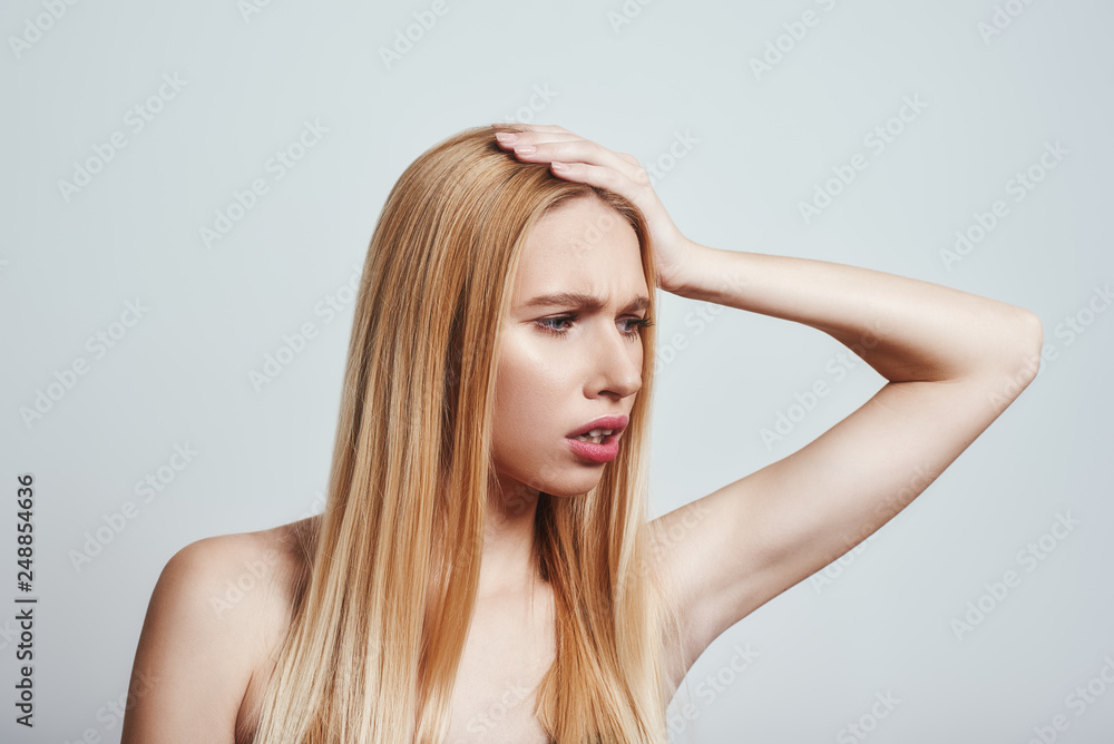 Pain is awful. Young blonde woman feeling sick and suffering from headache while standing on a grey background Pain is awful. Young blonde woman feeling sick and suffering from headache while standing on a grey background