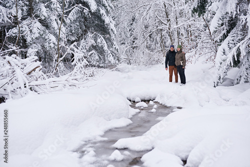 Smiling couple standing by a frozen river while out hiking