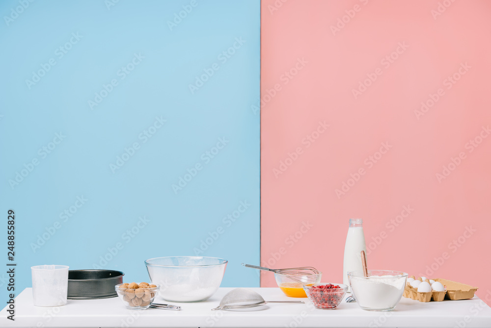 Fototapeta premium various cooking ingredients and utensils on white kitchen table on bicolor background