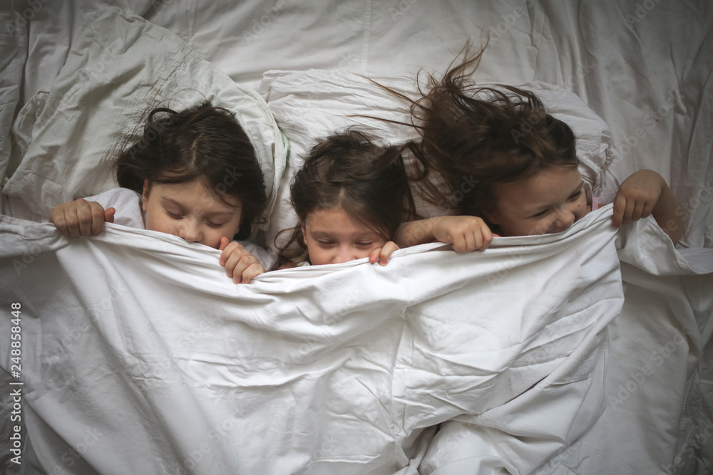 funny kids hiding under blanket wake up. Real bed