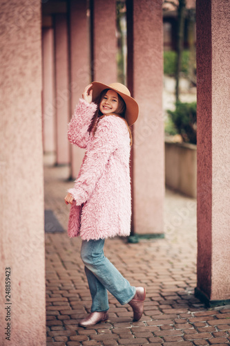 Outdoor fashion portrait of young girl wearing pink faux fur coat, street style