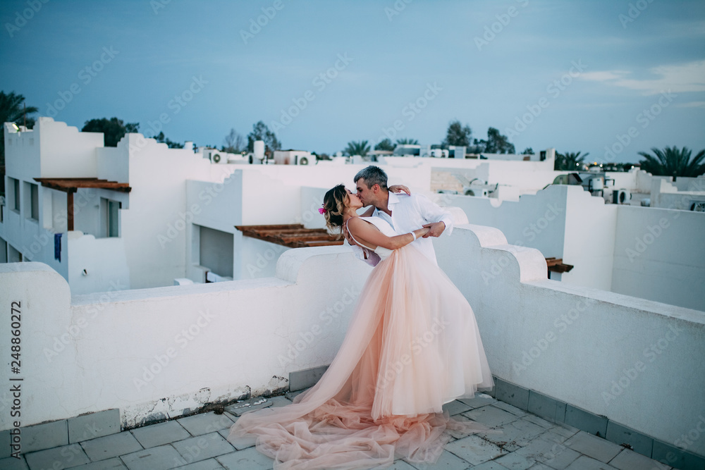 Φωτογραφία Happy newlyweds kiss on the roof of white house during the honeymoon in Egypt