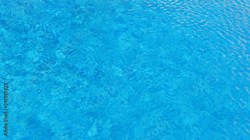 Swimming pool water background with texture of water surface with ripple effect, concept for summer vacation or spa, relaxation or working from anywhere, natural pattern with copy space