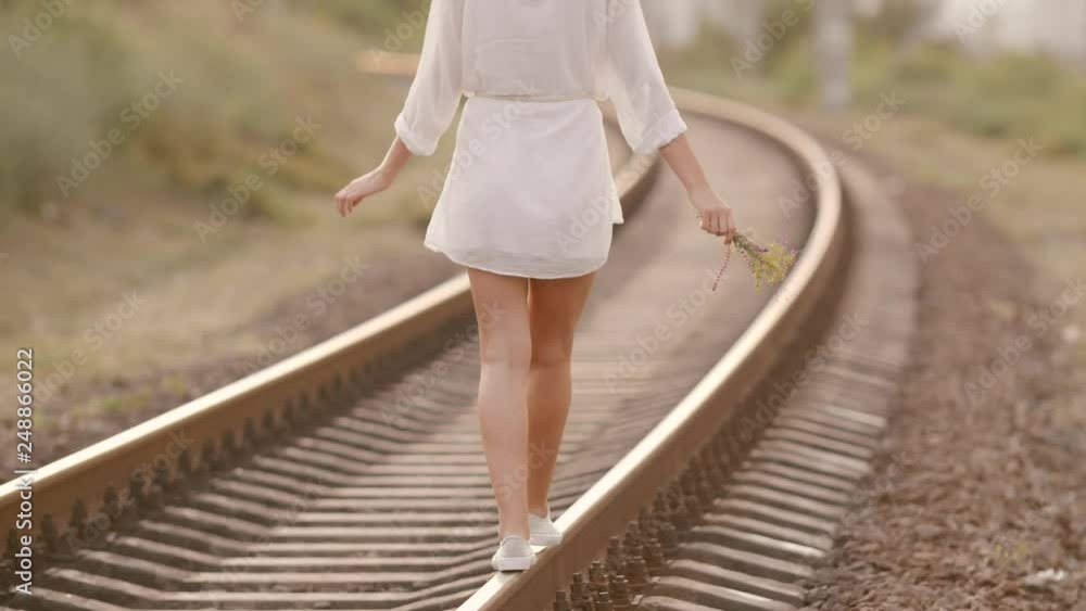Woman balancing on train rail. Beauty, freedom, summer travel concept. Woman balancing on train rail. Beauty, freedom, summer travel concept.