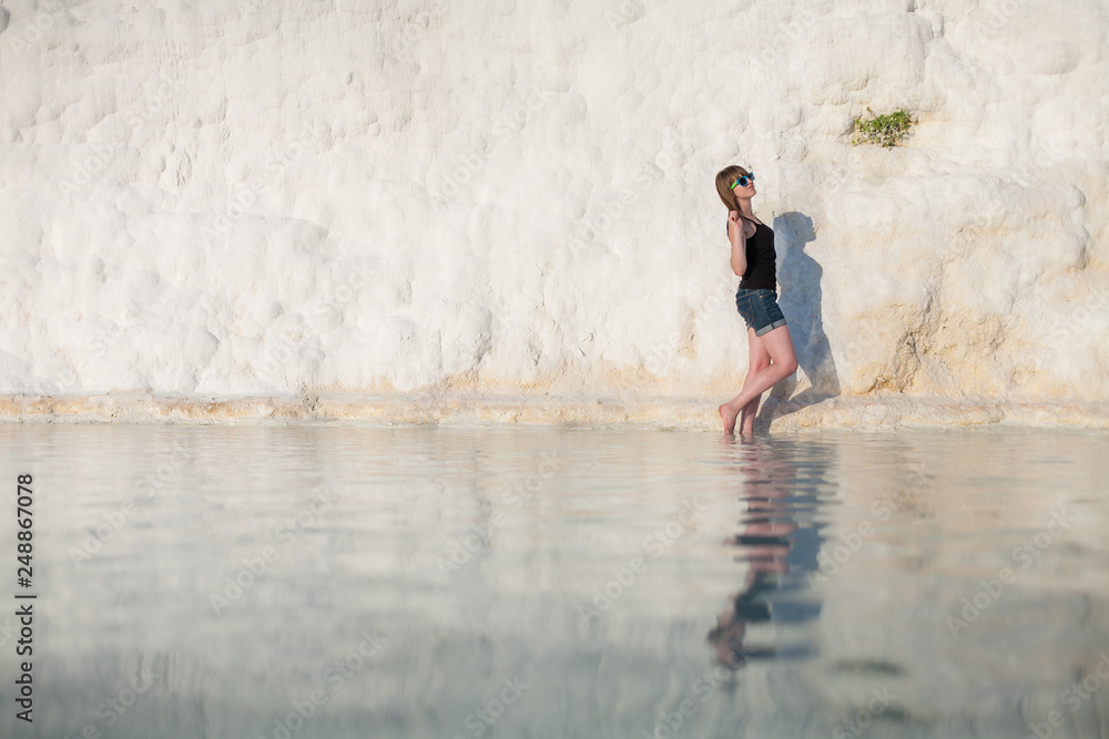 Natural travertine pools and terraces in Pamukkale. Cotton castle in southwestern Turkey, girl standing in natural pool. A woman in the pool of thermal springs and travertine Pamukkale