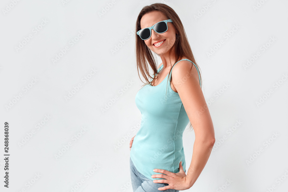 Freestyle. Woman in sunglasses standing studio isolated on white posing to camera happy side view Freestyle. Woman in sunglasses standing studio isolated on white posing to camera happy side view