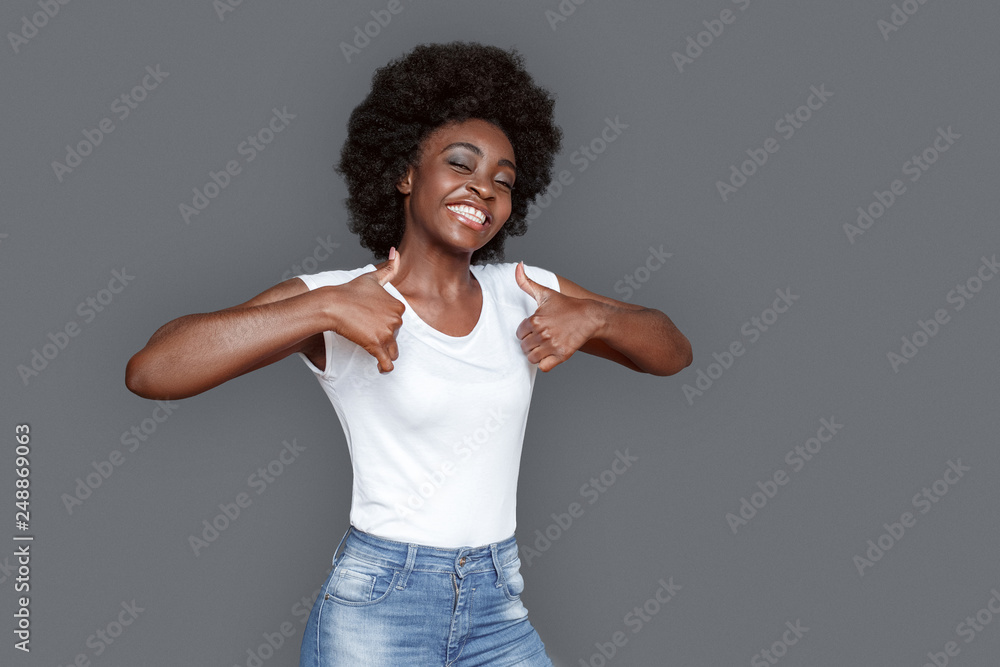 Young woman standing isolated on gray showing thumbs up smiling joyful Young woman standing isolated on gray showing thumbs up smiling joyful