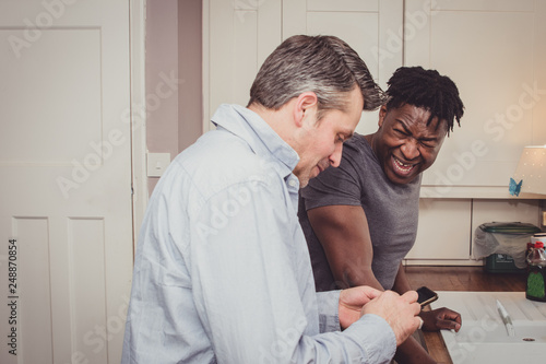 A gay couple sharing stories from their day at work over a slice of toast and a cup of tea and coffee in the evening. 