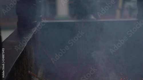 Asian people praying in Nankunshen Daitian Temple. Worshipers hand holding a necklace, used smoke of inciense for blessing. Taoist temple in chinese new year. Performing religious rituals-Dan photo