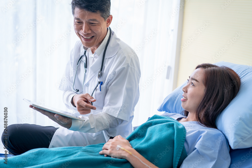 Doctors are explaining something from a tablet to a sick woman patient. Doctors are explaining something from a tablet to a sick woman patient.