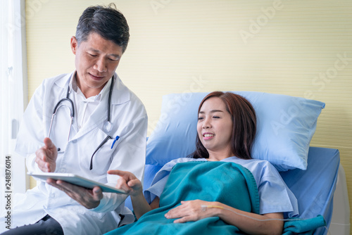 Doctors are explaining something from a tablet to a sick woman patient.