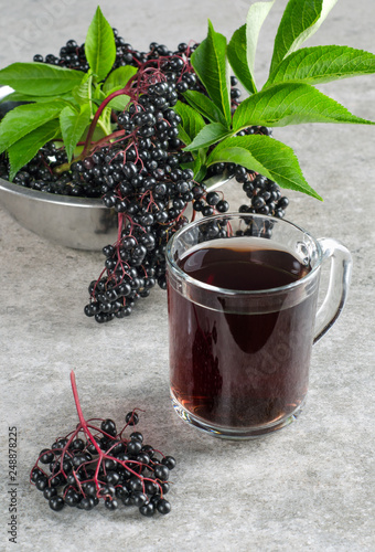 Glass with elderberry drink and clusters of berries