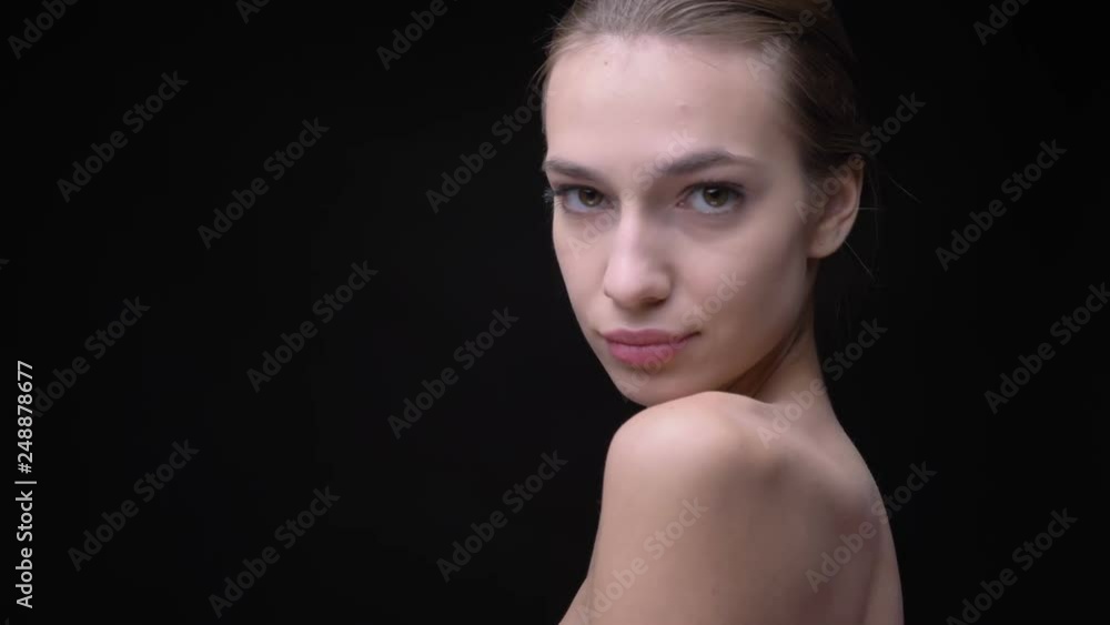 Portrait in profile of slim caucasian girl with nude make-up slowly moving and watching into camera on black background. Portrait in profile of slim caucasian girl with nude make-up slowly moving and watching into camera on black background.