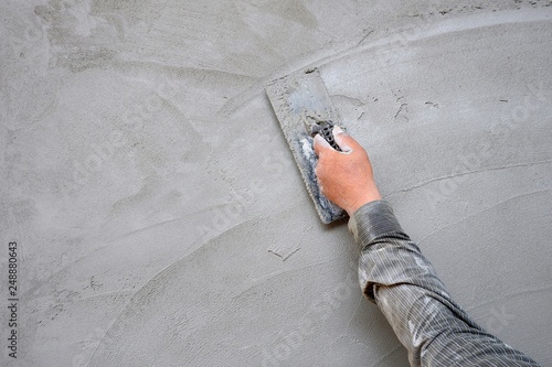 Plasterer man hand using trowel to plastering cement on concrete wall  photo