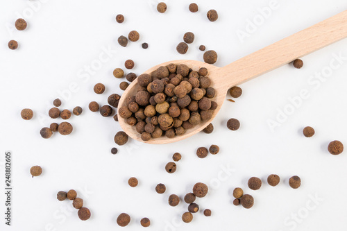 Allspices or Jamaica pepper in wooden spoon isolated on white background. Closeup.