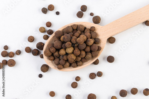 Allspices or Jamaica pepper in wooden spoon isolated on white background. Top view.