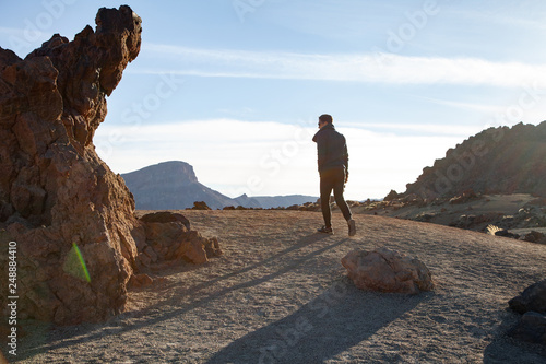 A young traveler walks along a volcanic mountain on top.