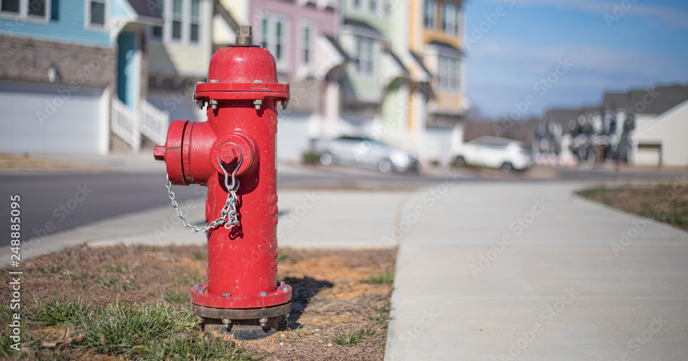 Close up bokeh shot of a bright red fire hydrant with brightly colored townhouses in the background.