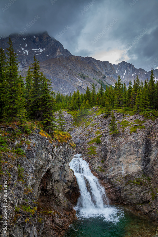 A small waterfall in the Canadian Rocky Mountains on a grey rainy day, Alberta, Canada