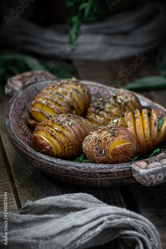 Baked whole potatoes with herbs and spices. Food photography in a rustic style.