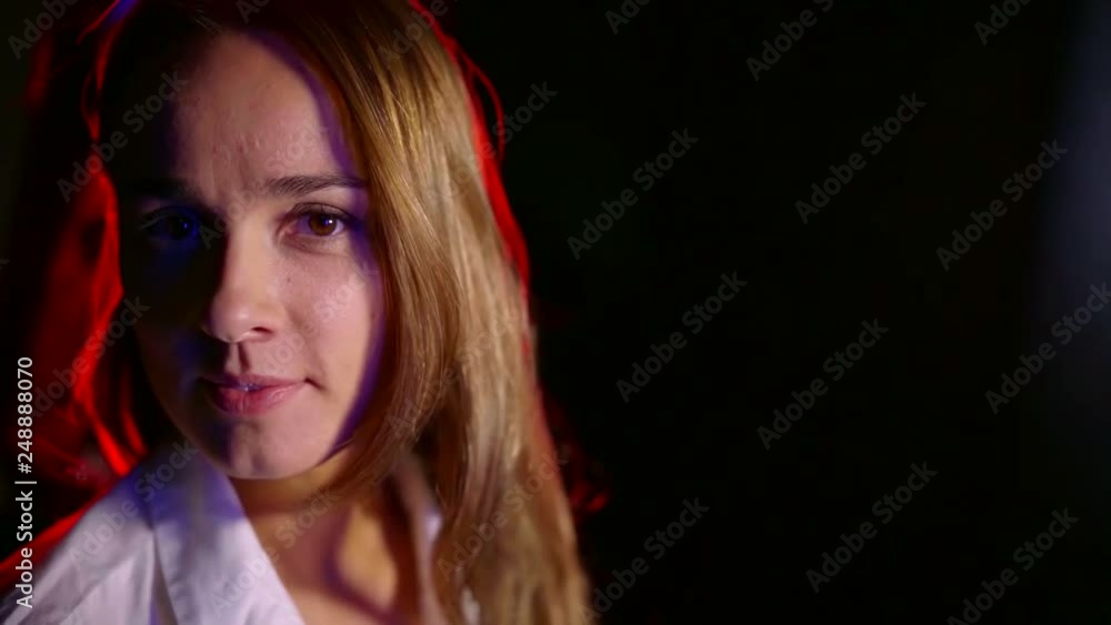 Close up. Portrait of charming middle-aged girl in a dark room looking at the camera and smiling Close up. Portrait of charming middle-aged girl in a dark room looking at the camera and smiling