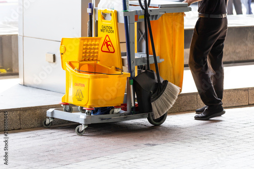 Janitorial and mop bucket on cleaning in process and worker on work.