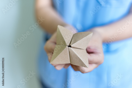 Woman's hands holding a paper fortune teller on blue background photo
