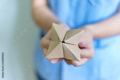 Obraz na plátne Woman's hands holding a paper fortune teller on blue background
