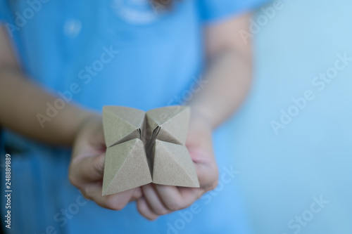 Tableau sur toile Woman's hands holding a paper fortune teller on blue background